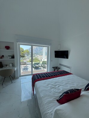A modern bedroom with a bed, a desk, and a TV.