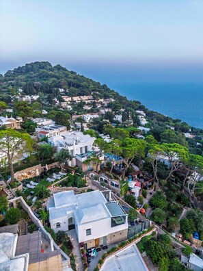 A coastal village with terraced houses, a central courtyard, and a view of the sea.
