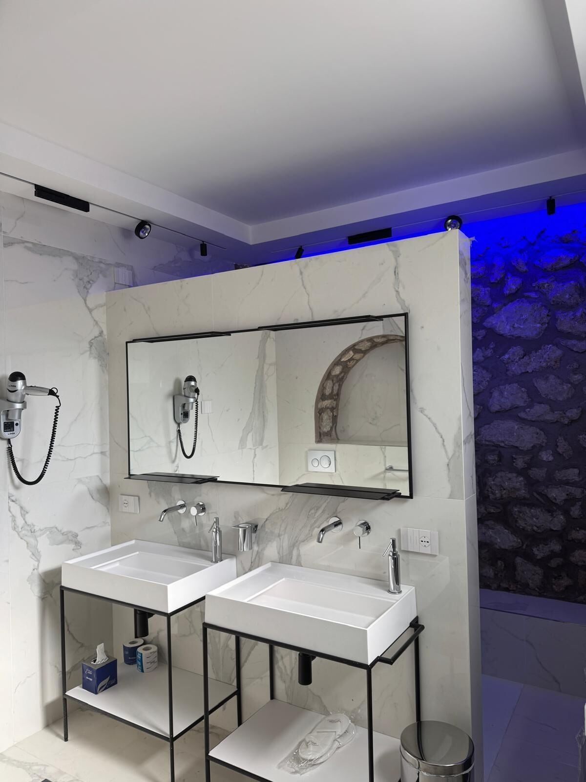 Un baño moderno con dos lavamanos, un espejo grande y una ducha.