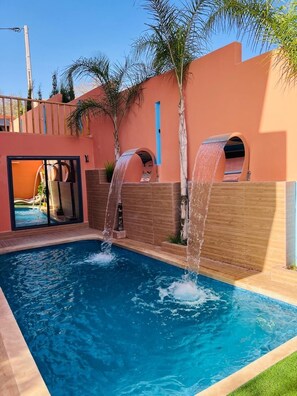 Una piscina con dos cascadas, un tobogán y vistas a una zona de resort.