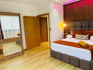 A hotel room with a large bed, a mirror, wooden wardrobe, and a wall-mounted light fixture. - Vrbo Property (Igui N'Targuit taghazout)