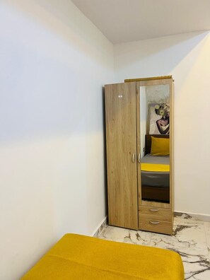 A room with a wooden wardrobe, a bed with a yellow bedspread, and a marble floor. - 🏡Anaya Villa — private pool, elegance, and absolute comfort. (Igui N'Targuit taghazout)