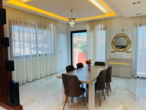 A modern dining area with a marble floor, a wooden table, and six chairs. - Vrbo Property (Igui N'Targuit taghazout)