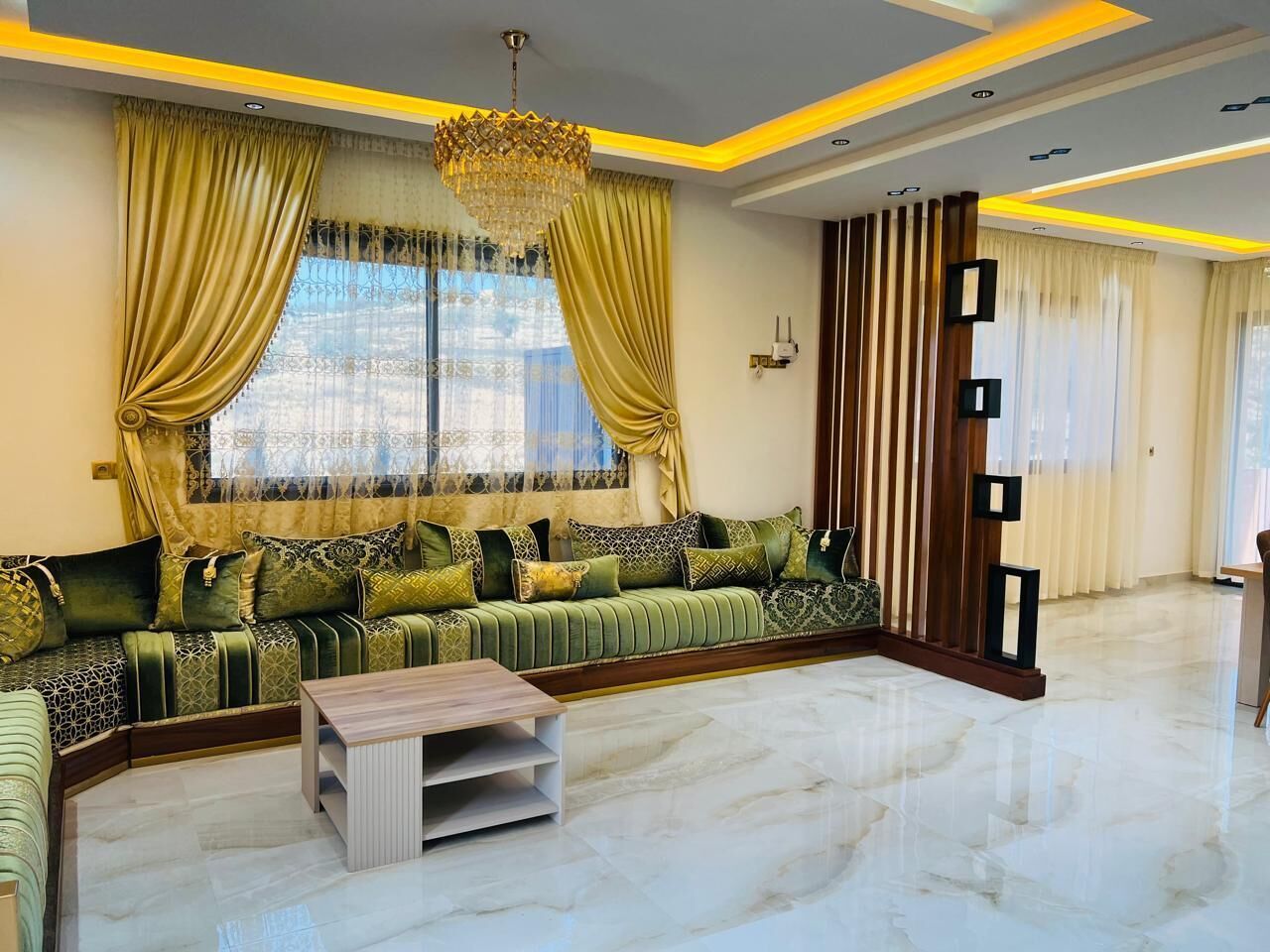 A modern living room with a sectional sofa, a coffee table, and a decorative wall panel.