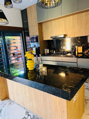 Una cocina moderna con encimera de mármol negro, armarios de madera y horno empotrado.