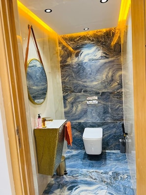 A bathroom with a marble wall, a white toilet, and a sink with a towel. - Vrbo Property (Igui N'Targuit taghazout)