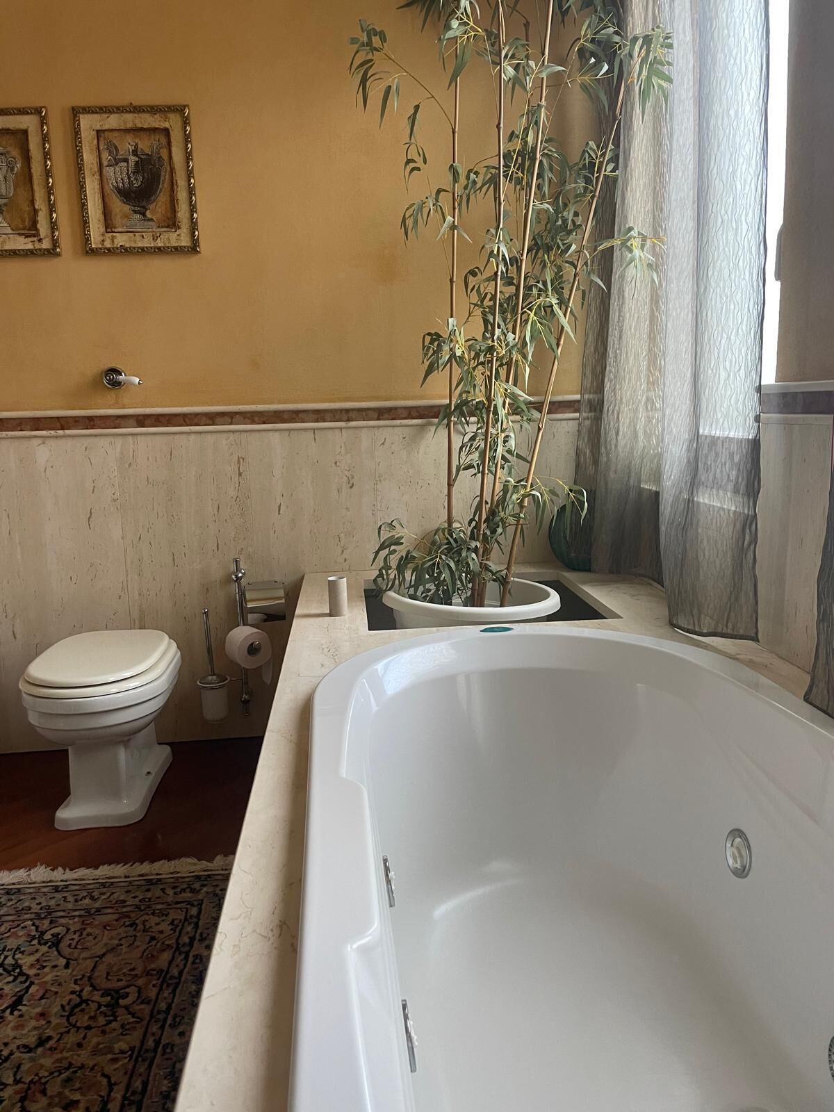 Ein Badezimmer mit einer Badewanne, Toilette und einer Zimmerpflanze.