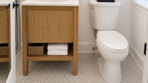 A bathroom with a white sink, a round mirror, a toilet, and wooden shelves with towels and a plant. - 1-Bedroom Hotel Suite in Historical San Francisco, close to AI Conference (San Francisco)