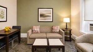 A living room with a sofa, two side tables, a coffee table, a dining table with chairs, and a fruit bowl. - 1-Bedroom Hotel Suite in Historical San Francisco, close to AI Conference (San Francisco)