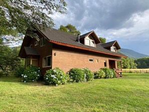 A two-story wooden house with a sloped roof, a porch, and a fenced yard. - Vrbo Property (Pucon)