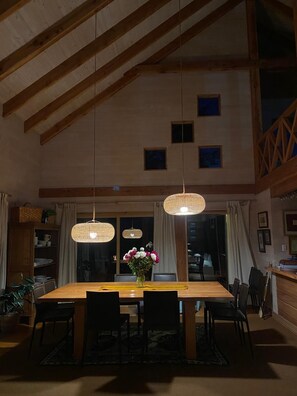 A dining area with a wooden table, chairs, and hanging pendant lights. - Vrbo Property (Pucon)