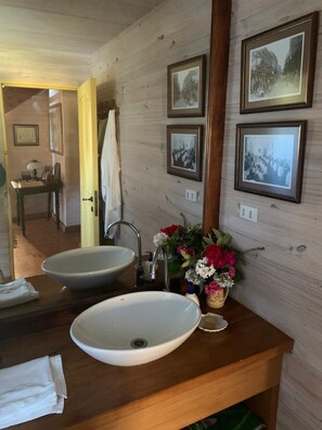 A bathroom with two sinks, a mirror, and framed photographs on the wall.