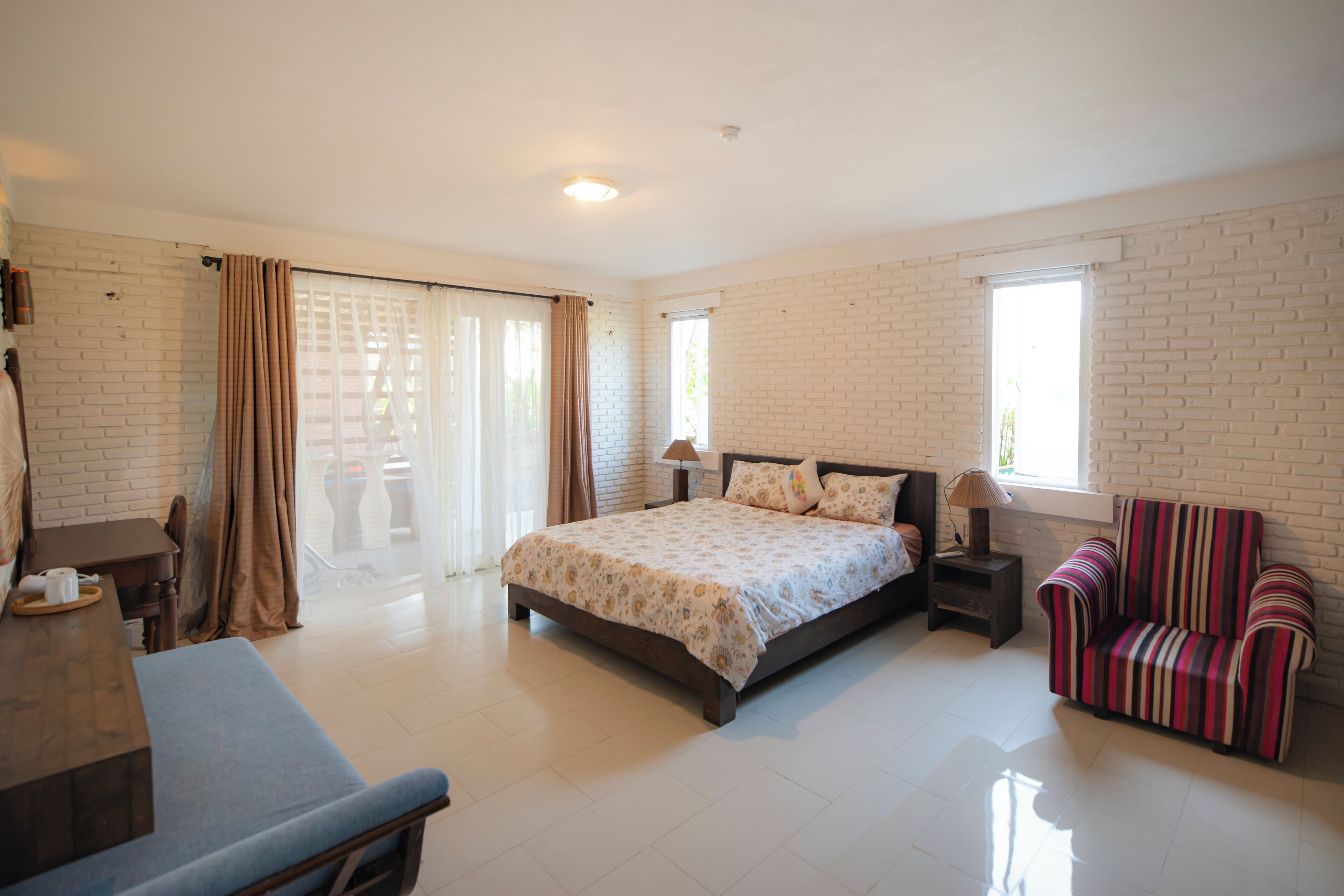 A bedroom with a bed, a chair, a desk, and a window.