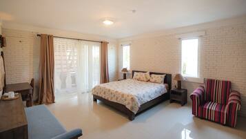 A bedroom with a bed, a chair, a desk, and a window.