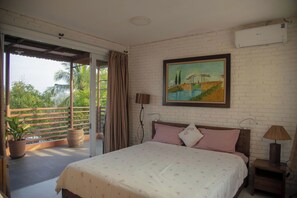 Un dormitorio con cama, un cuadro, una ventana y un balcón con plantas.