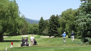 A golf course with a cart, a golf bag, and a golfer in the distance. - Across Stree from Ski Resort Base | Hot Tub | Managed by Park City Lodging (Park City)
