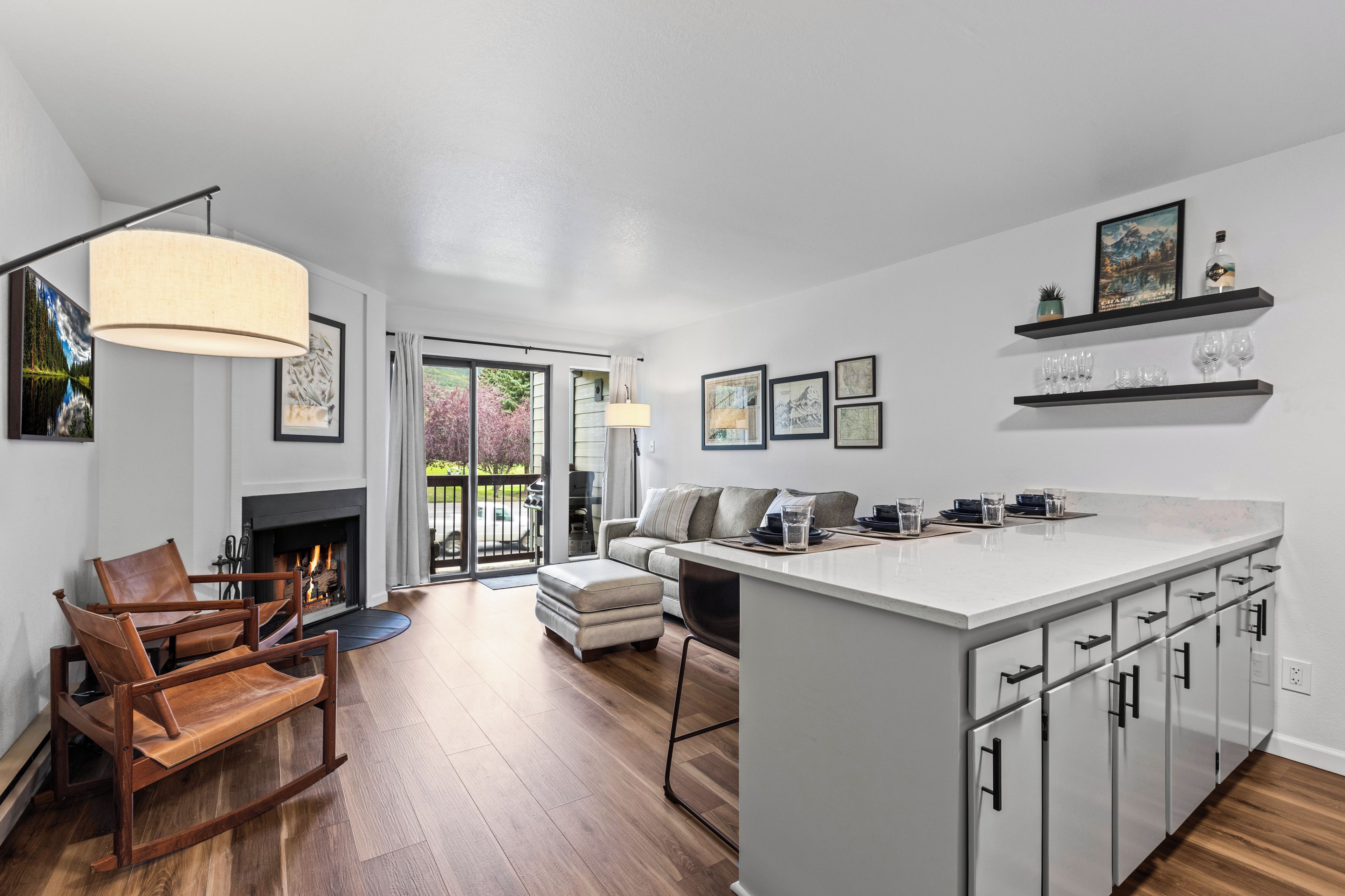 A modern kitchen with a central island, wooden flooring, and a fireplace.