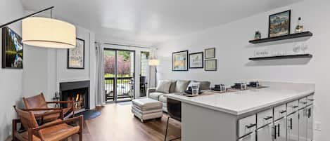 Une cuisine moderne avec un îlot central, un plancher en bois et une cheminée.