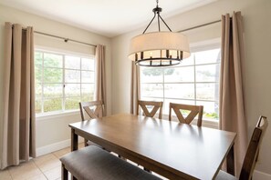 A dining area with a table, chairs, and a hanging light fixture. - Balboa park Craftsman home (San Diego)