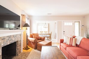 A living room with a fireplace, a television, a sofa, and a dining area. - Balboa park Craftsman home (San Diego)