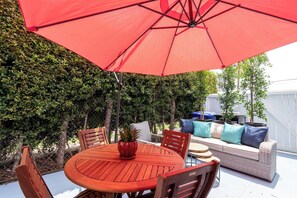 A patio with a round wooden table, chairs, a red umbrella, and a wicker sofa with cushions. - Balboa park Craftsman home (San Diego)