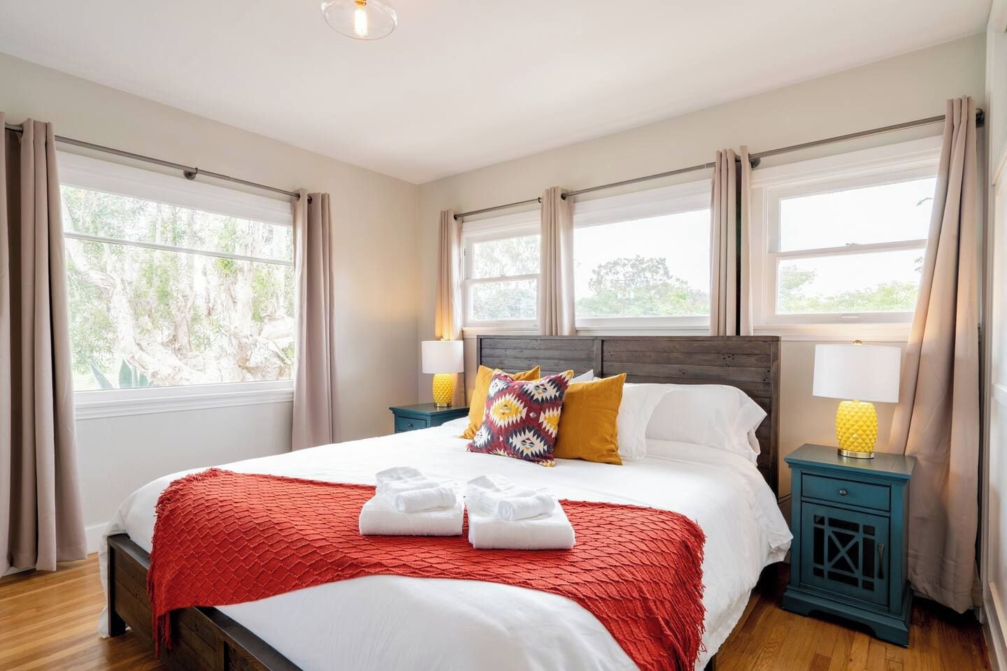 A hotel room with a large bed, two bedside tables, and a window with curtains.