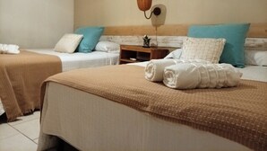 A hotel room with two beds, a bedside table, a wall-mounted mirror, and a small plant.