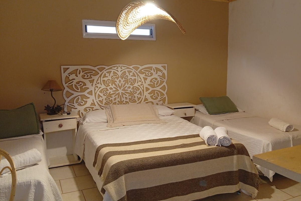Una habitación de hotel con una cama, una cama adicional, una mesita de noche, una lámpara y una ventana.