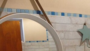 A bathroom with a white sink, a mirror, a wooden door, and a blue star decoration on the wall.