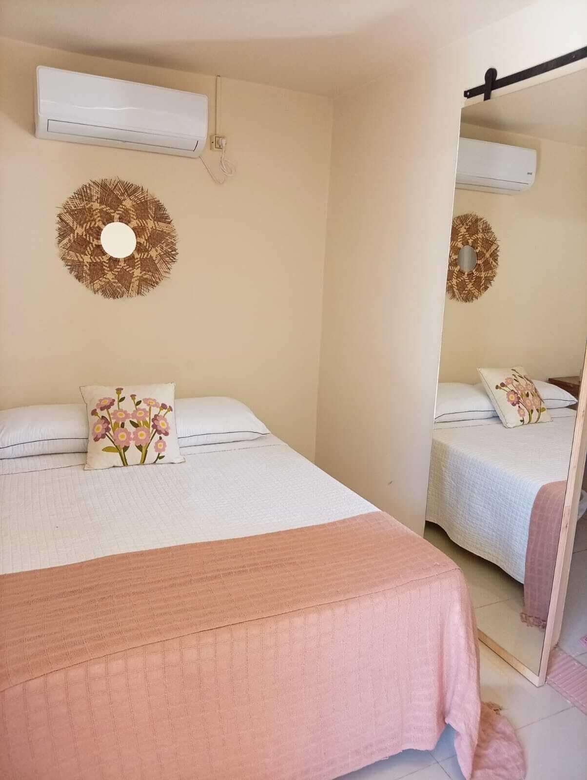 Une chambre avec deux lits, un miroir et des climatiseurs fixés au mur.