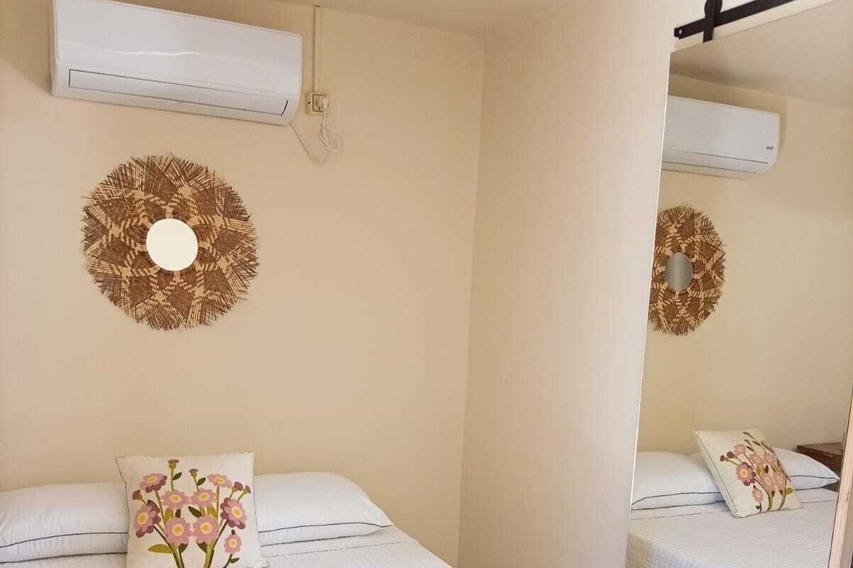 Un dormitorio con dos camas, un espejo y unidades de aire acondicionado instaladas en la pared.