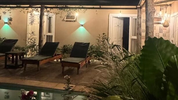 A nighttime outdoor area with a pool, lounge chairs, and ambient lighting.