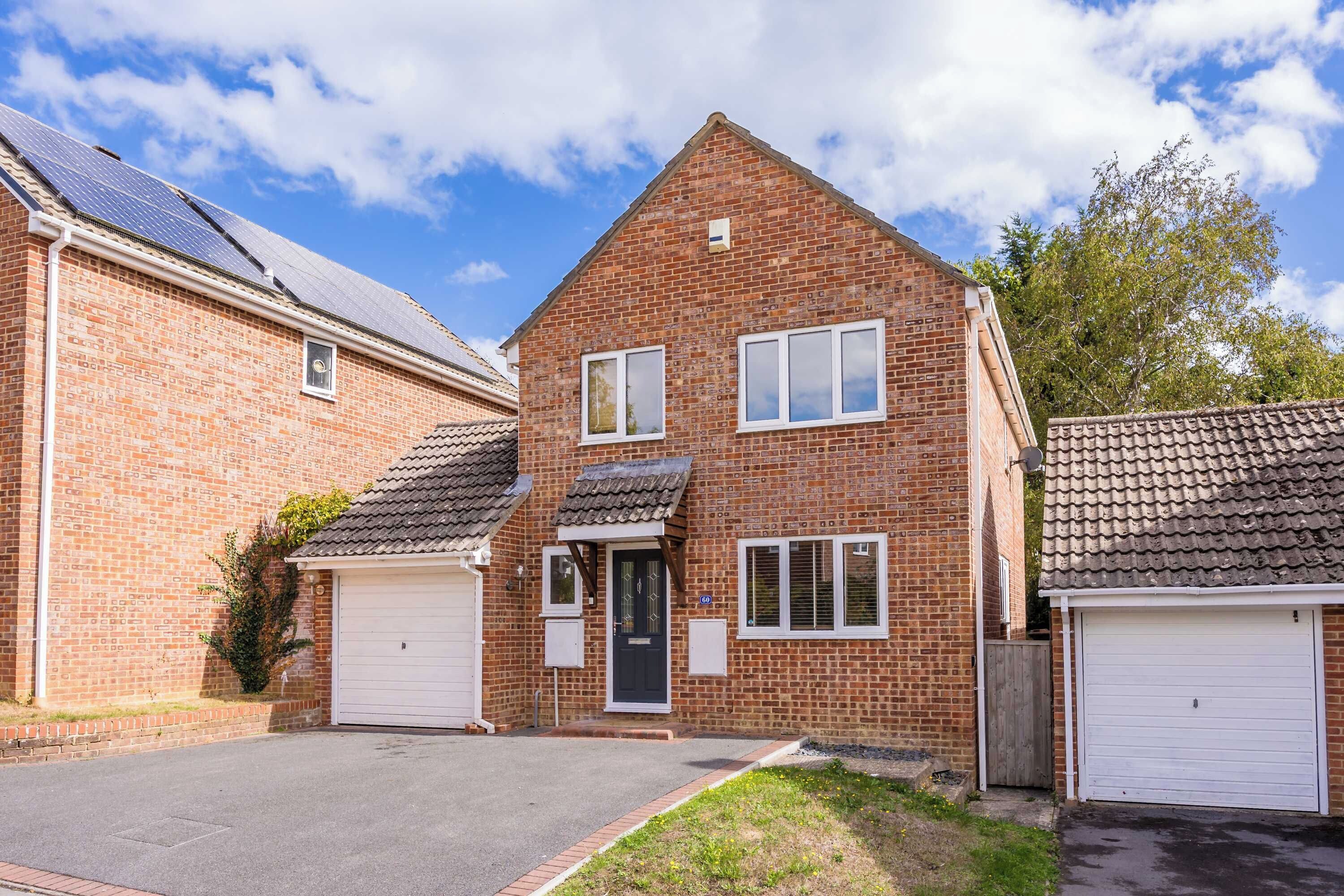 A two-story brick house with a garage, a front door, and a small garden area.