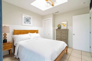 Ein Schlafzimmer mit einem Bett, einem Nachttisch, einer Kommode, einem Globus und einem gerahmten Bild an der Wand.