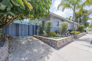 Ein Wohnhaus mit einer Steismauer, einem blauen Zaun und verschiedenen Pflanzen.