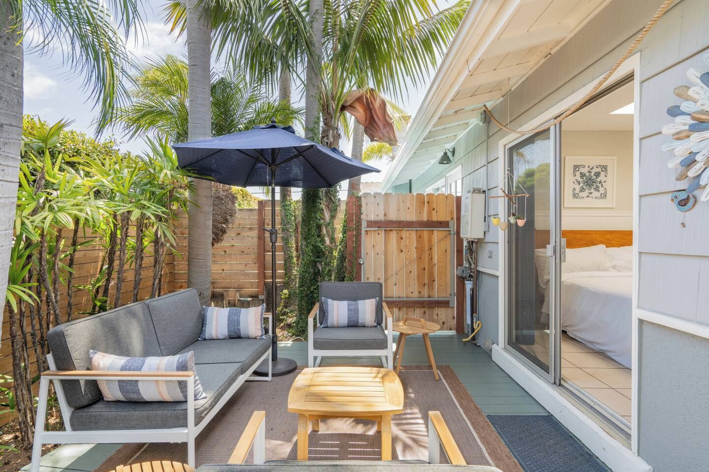 A patio with a sofa, chairs, and an umbrella.