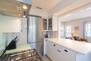 A modern kitchen with a gas stove, stainless steel appliances, and white cabinetry. - Balboa Park bungalow with palm veranda (San Diego)