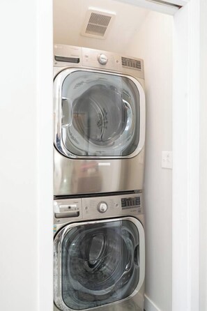 A compact laundry room with two stacked front-loading washing machines. - Balboa Park bungalow with palm veranda (San Diego)