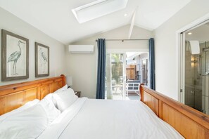Een hotelkamer met een groot bed, een houten hoofdeinde, een dakraam, uitzicht naar buiten en een douchecabine met glazen wanden.