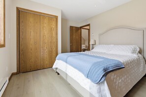 Ein Schlafzimmer mit einem Doppelbett, einem Holzschrank und einem Spiegel an der Wand.