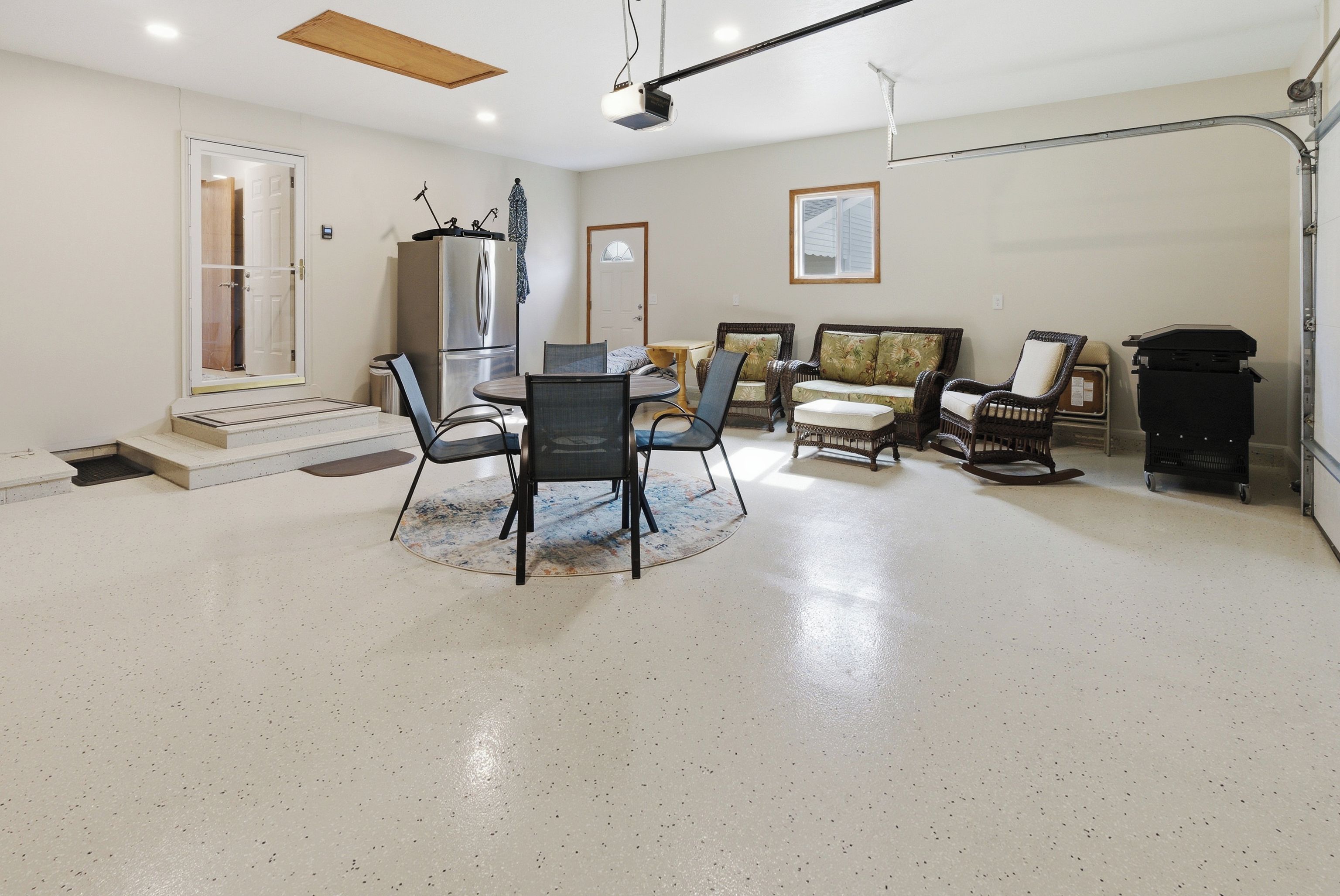 A spacious living room with a dining area, a large window, and a ceiling-mounted projector.