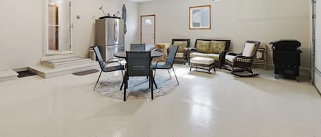 A spacious living room with a dining area, a large window, and a ceiling-mounted projector.