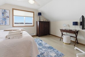 Een slaapkamer met een bed, een bureau, een kaptafel en een raam met uitzicht.