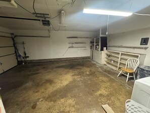 Ein Zimmer mit Betonboden, einem weißen Stuhl, einem weißen Regal und einer weißen Waschmaschine.