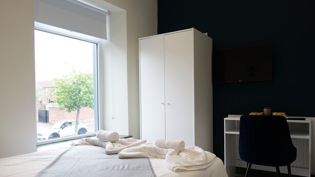 Ein Schlafzimmer mit Bett, Kleiderschrank, Schreibtisch und Stuhl.