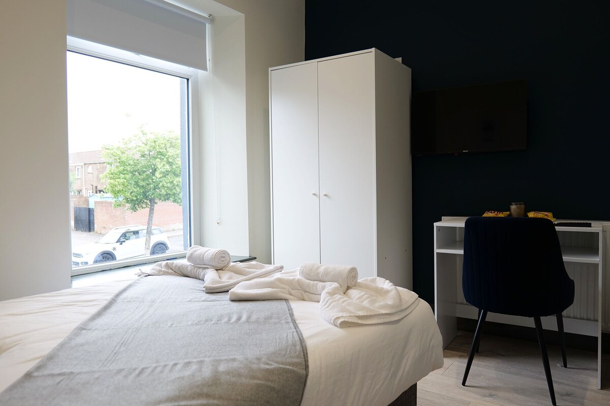 A bedroom with a bed, a wardrobe, a desk, and a chair.