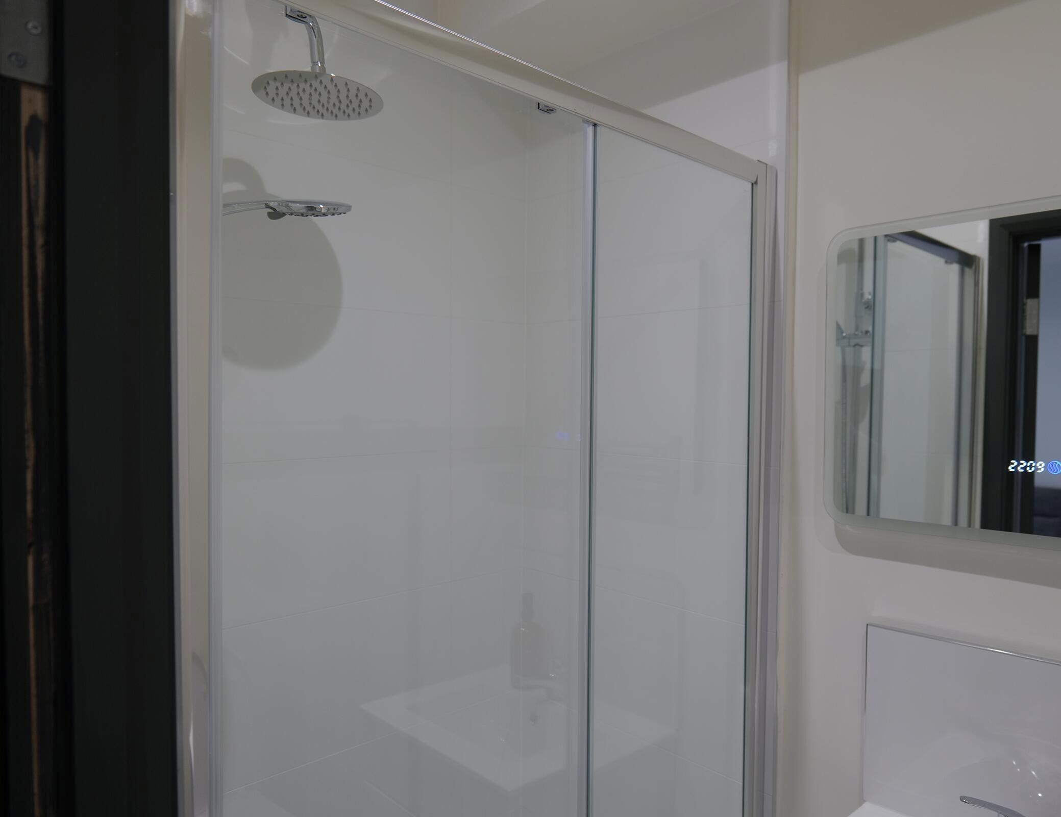 Ein modernes Badezimmer mit einer Duschkabine, einem Spiegel und einem Waschbecken.
