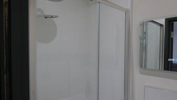 Ein modernes Badezimmer mit einer Duschkabine, einem Spiegel und einem Waschbecken.