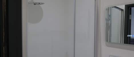 Un baño moderno con cabina de ducha de vidrio, un espejo y un lavabo.