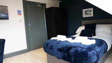 Ein Schlafzimmer mit Bett, Tür, Lichtschalter und Brandschutzschild.